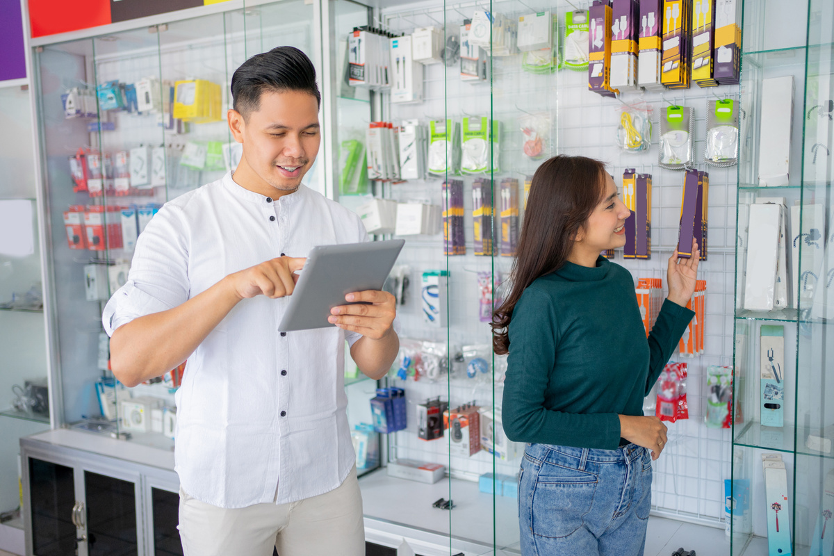 Business Man Using a Tablet with a Woman Choosing Mobile Phone Accessories Products